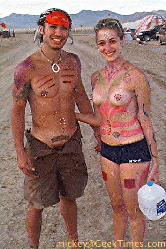 A couple adorned with body piercings, tattos, and paint.